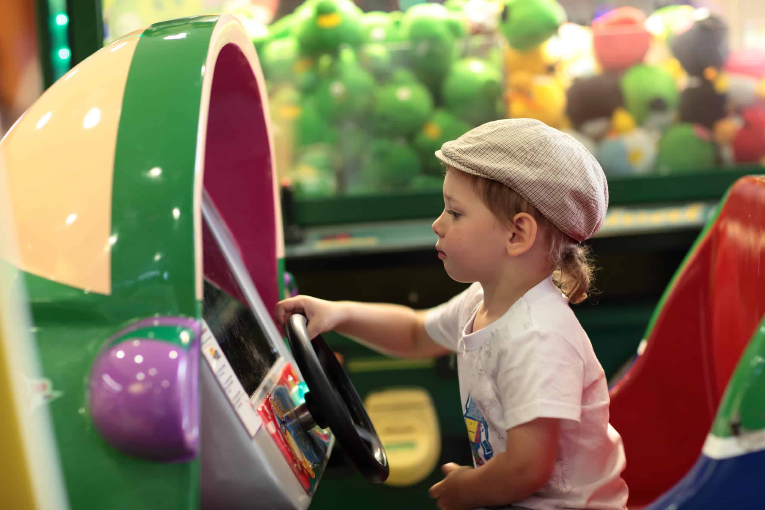 Boy playing arcade game machine at an amusement park